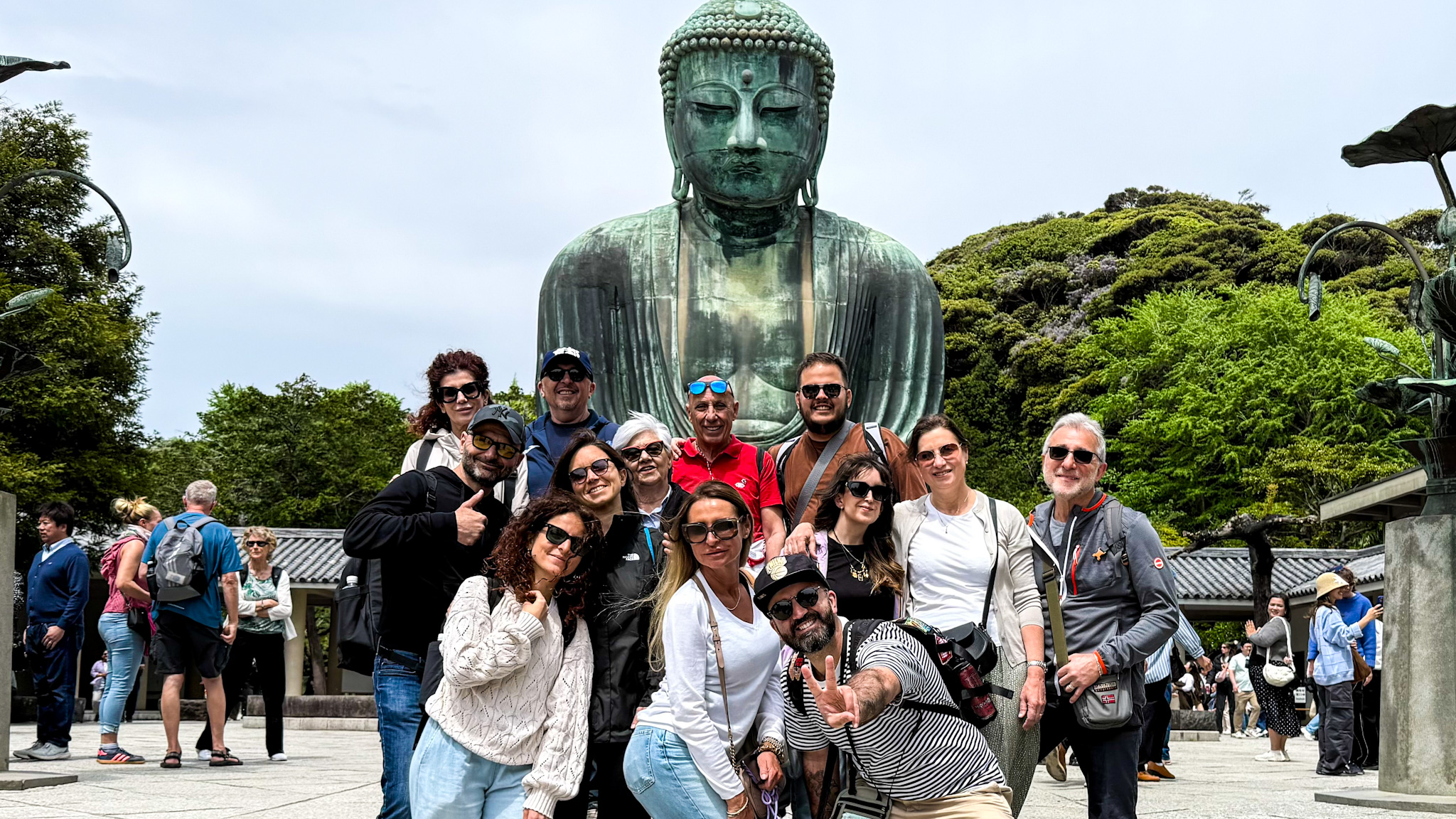 Foto di gruppo davanti al grande Buddha di Kamakura. 13 persone in posa